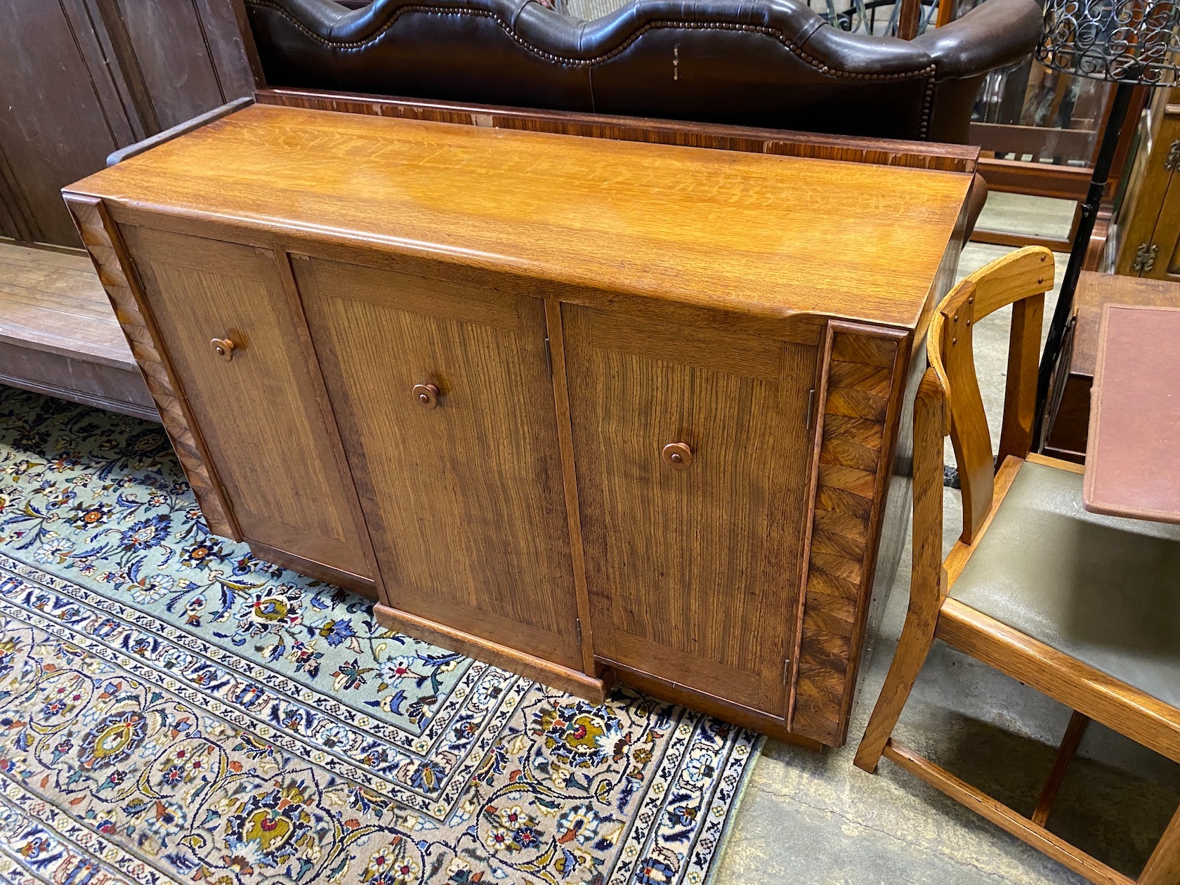 An early 20th century oak and zebra wood dining suite by Ebenezer Gomme, comprising draw leaf table, four chairs and sideboard